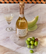 Load image into Gallery viewer, Top view of Blanc de Blancs Sparkling Non-Alcoholic Wine with glass and fruit